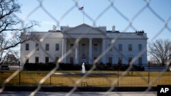 In this March 4, 2013, photo, The White House is seen through a chain-link fence where the inaugural reviewing stand once stood in Washington.