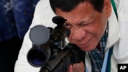 In this June 28, 2017 photo, Philippine President Rodrigo Duterte checks the scope of a Chinese-made CS/LR4A sniper rifle.