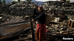 An earthquake victim cuts wood from the debris of her house in Barpak village, the epicenter of the April 25 earthquake in Nepal.
