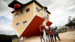 People pose for a photo outside the upside down house, in Guatavita, Colombia, January 23, 2022. Picture taken January 23, 2022. REUTERS/Luisa Gonzalez