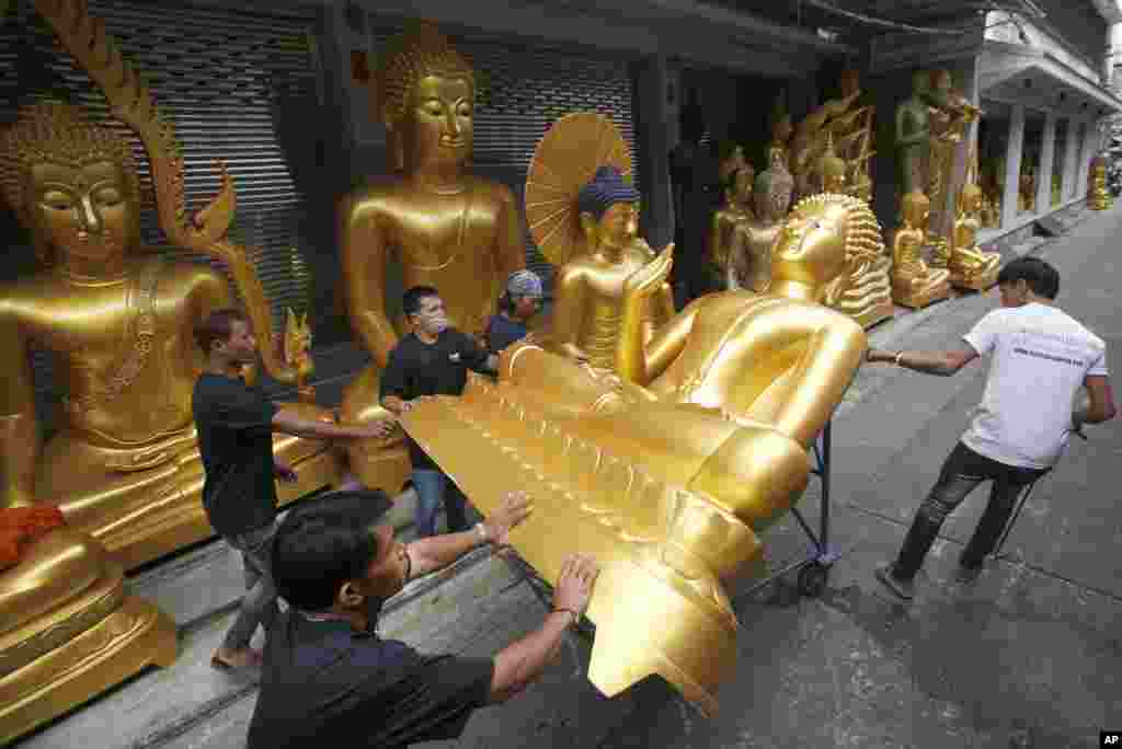 Workers move a Buddha statue at a shop in Bangkok, Thailand, in preparation for the upcoming Buddhist Lent.