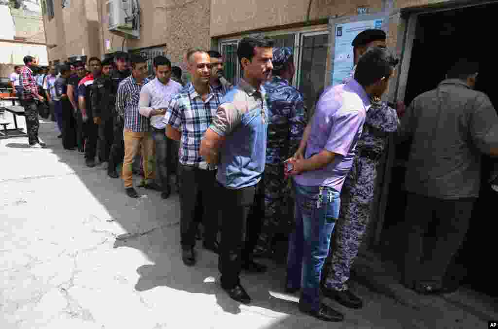 Iraqi security forces stand in line to vote outside a polling center, Baghdad, April 28, 2014.