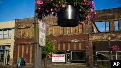 Dilapidated storefronts stand along baskets of pink petunias that hang from light posts all over town, watered regularly by residents trying to make their city feel alive again in Aberdeen, Wash., June 16, 2017. Six months into Donald Trump's presidency, his supporters in this county, battered by drugs and death, maintain differing degrees of faith that he will make good on his promise to fix the economy. 