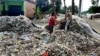 Supiati dan Saji mengangkut sampah plastik impor di pekarangan mereka, di Desa Bangun, Kecamatan Pungging, Kabupaten Mojokerto, untuk kemudian disortir dan dijual kembali. (Foto: Petrus Riski/VOA)