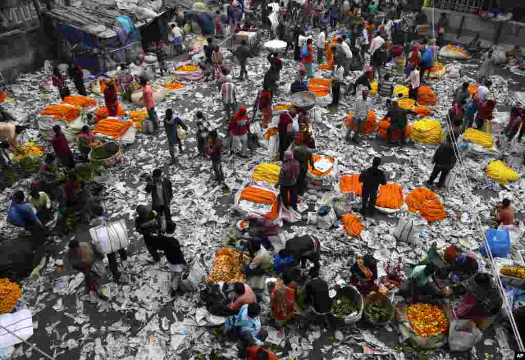 People sell marigold flowers at a market covered with paper used for packaging, in Kolkata, India.