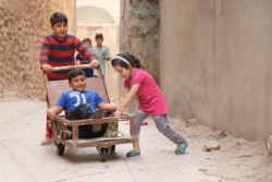 Children in Mosul's Old City play with makeshift toys in the ancient alleyways, in Mosul, Iraq, Oct. 13, 2021. Parents say the area is safe, but some worry about IS militants attempting to return to power. (VOA/Heather Murdock)