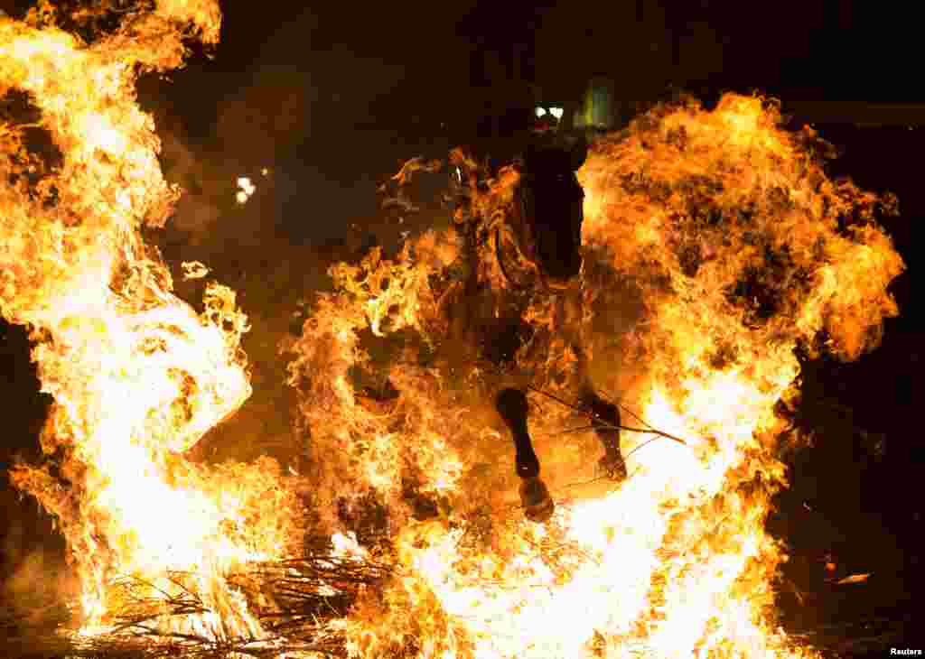A man rides a horse through the flames during the &quot;Luminarias&quot; annual religious celebration on the eve of Saint Anthony&#39;s day, Spain&#39;s patron saint of animals, in the village of San Bartolome de Pinares, northwest of Madrid, Jan. 16, 2017.