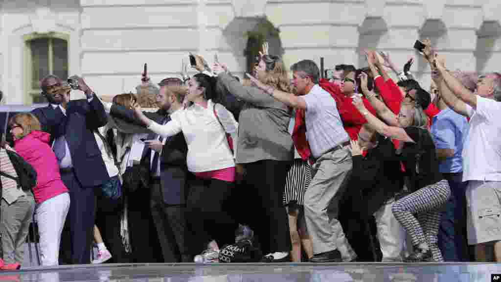 Le personnel du Congrès et des invités se bousculent pour photographierle pape François qui repart du Capitole à bord de sa Fiat 500L après son discours devant le Congrès, à Washington, 24 septembre 2015.