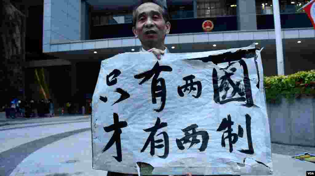 支持港獨的梁先生手持示威牌突破保安人員阻攔進入公民廣場。（美國之音湯惠芸）