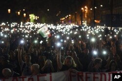 FILE - Protesters hold up lit mobiles phones during a rally against legislation that could force the closure of the Soros-founded Central European University, in front of Parliament, in Budapest, Hungary, April 2, 2017.