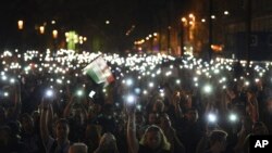 FILE - Protesters hold up lit mobile phones during a rally against legislation that could force the closure of the Soros-founded Central European University, in front of Parliament, in Budapest, Hungary, April 2, 2017.