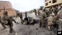 American and Afghan soldiers inspects the site of car bomb outside governor's compound in Parwan provincial capital of Charikar, some 30 miles (50 kilometers) north of Kabul, Afghanistan, August 14, 2011