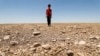 FILE - In this file photo a boy walks through a dried up agricultural field in the Saadiya area, north of Diyala in eastern Iraq on June 24, 2021