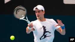 In this photo supplied by Tennis Australia, defending champion Serbia's Novak Djokovic practices in the Rod Laver Arena ahead of the Australian Open at Melbourne Park in Melbourne, Australia, Tuesday, Jan. 11, 2022. 