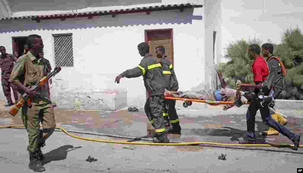 Somali rescuers carry away the dead body of a civilian from the scene of a twin bombing attack on a hotel in the capital Mogadishu, Somalia.