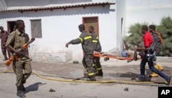 Somali rescuers carry away the dead body of a civilian from the scene of a twin bombing attack on a hotel in the capital Mogadishu, Somalia, Feb. 20, 2015.