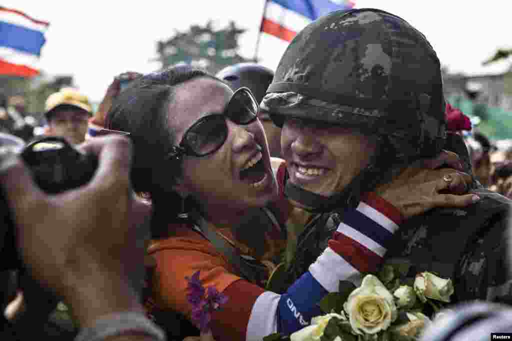 An anti-government protester hugs a Thai soldier, after some of the police personnel stationed in the Government house left the place following an agreement between the army and protesters, in Bangkok, Thailand.