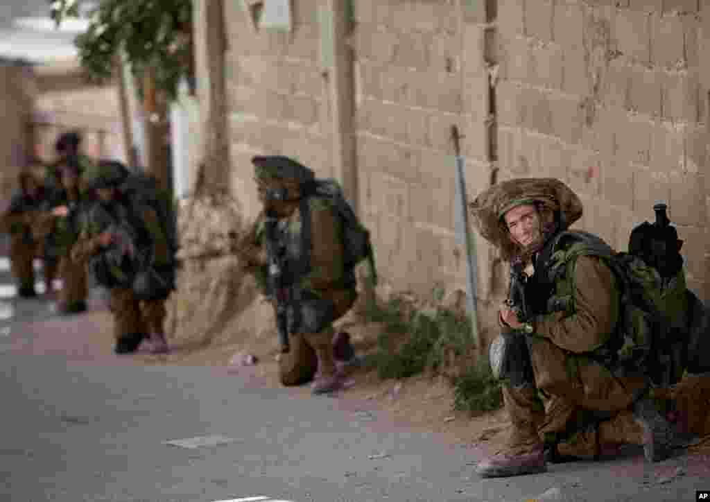 Israeli soldiers take positions during a military operation searching for three missing teenagers, near the West Bank city of Hebron, June 15, 2014. 