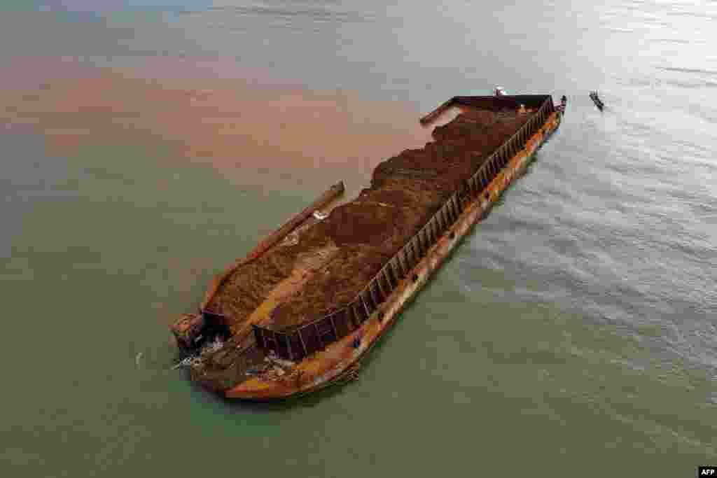 Fishing boats are seen next to a barge that sank and polluted the sea in the waters off the Gong Beach tourist area in Konawe regency, southeast Sulawesi, Indonesia.