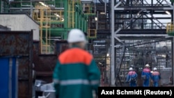 Seorang karyawan berjalan melalui kilang minyak Petrolchemie and Kraftstoffe (PCK) di Schwedt/Oder. Kilang PCK dimiliki bersama oleh BP, Shell, Eni, Total dan Rosneft. Sebagian besar minyak mentah dikirim oleh pipa Rusia Druschba dari Siberia barat. (Foto