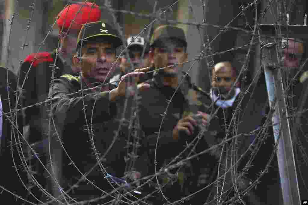 An Egyptian officer, left, attempts to talk to protesters behind a newly erected barbed wire barricade by the Egyptian army near Tahrir square in Cairo, November 24, 2011. (AP)