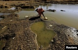 An internally displaced woman collects water from a pond to construct a mud-house at the Aboushok camp in El Fasher, North Darfur, Sudan, Nov.17, 2015.