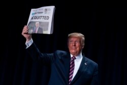El presidente Donald Trump muestra el diario USA Today con el titular "Absuelto" durante el Desayuno Nacional de Oración en Washington el jueves, 6 de febrero de 2020.