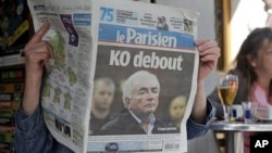 A woman reads the French newspaper "Le Parisien" headlining on IMF head arrest, in Paris, Tuesday, May 17, 2011