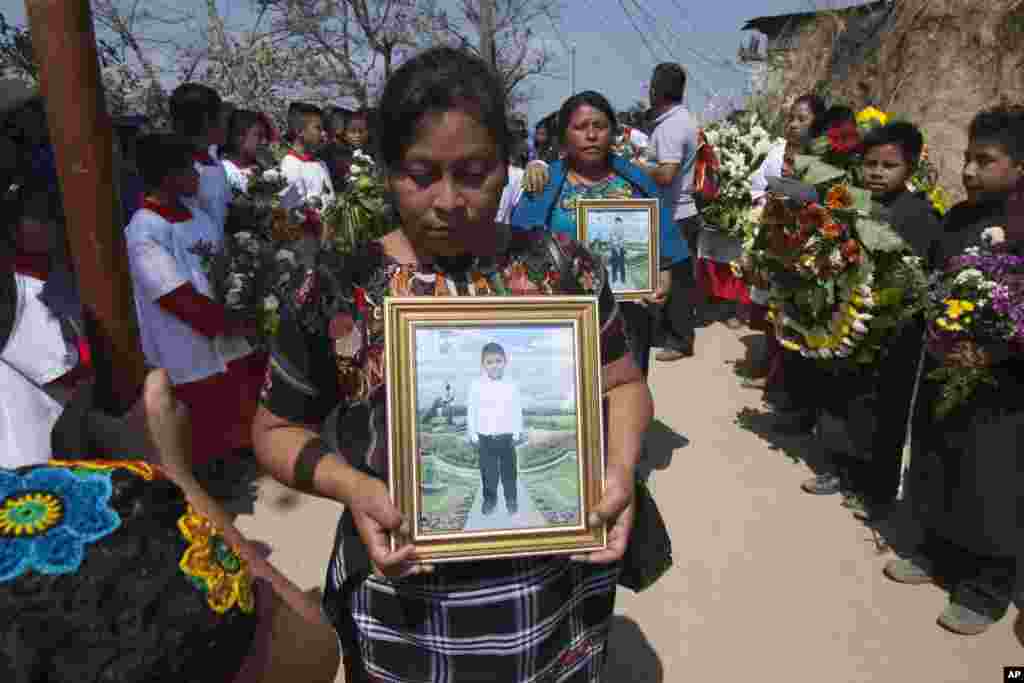 Relatives take part in a burial service, holding portraits of Carlos Daniel Xiquin, 10, front, and Oscar Armando Toc Cotzajay, 11, who were kidnapped over the weekend and then killed when the family could not raise the ransom money, in Ajuix, Guatemala, Feb. 14, 2017. Authorities found the bodies of the two boys on Sunday, stabbed and thrown into sacks in the municipality of San Juan Sacatepéquez, northwest Guatemala.