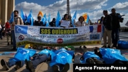 FILE - Supporters of the French Uyghur Community shout slogans and hold Uyghur flags during a demonstration over China's human rights record near the Eiffel Tower on March 25, 2019.