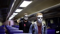 Dos personas que usan maquillaje de esqueleto caminan hacia las puertas de un tren cuando se acerca a la estación central de Ámsterdam, el domingo 27 de octubre de 2019.