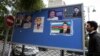A man passes an election poster with portraits of presidential candidates in central Baku, October 4, 2013.