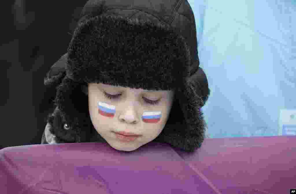 Một khán giả nhí với cờ Nga vẽ trên má tại điểm thi trượt ván của nam. Các cuộc tranh tài phải hủy bỏ do tầm nhìn hạn chế ở Công viên thể thao mạo hiểm Rosa Khutor, tại Thế vận hội mùa đông 2014 ở Krasnaya Polyana, Nga. 