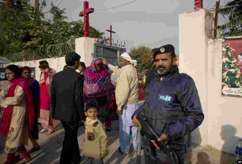 Masyarakat Kristen Pakistan meninggalkan gereja setempat setelah misa Natal yang dijaga oleh petugas kemanan, di Islamabad, Pakistan.