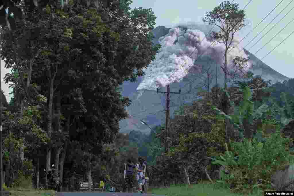 Locals walk on a road as Mount Merapi volcano spews hot ash in Kaliurang, Sleman, Yogyakarta, Indonesia.