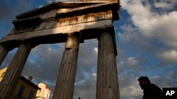 A man walks in front of the Gate of the ancient Roman agora, in central Athens.