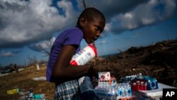 Ayfon Minus, 8, collects donated food that was brought by helicopter from Freeport to the Hurricane Dorian destroyed village of High Rock, Grand Bahama, Bahamas, Tuesday, September 10, 2019. (AP Photo/Ramon Espinosa)