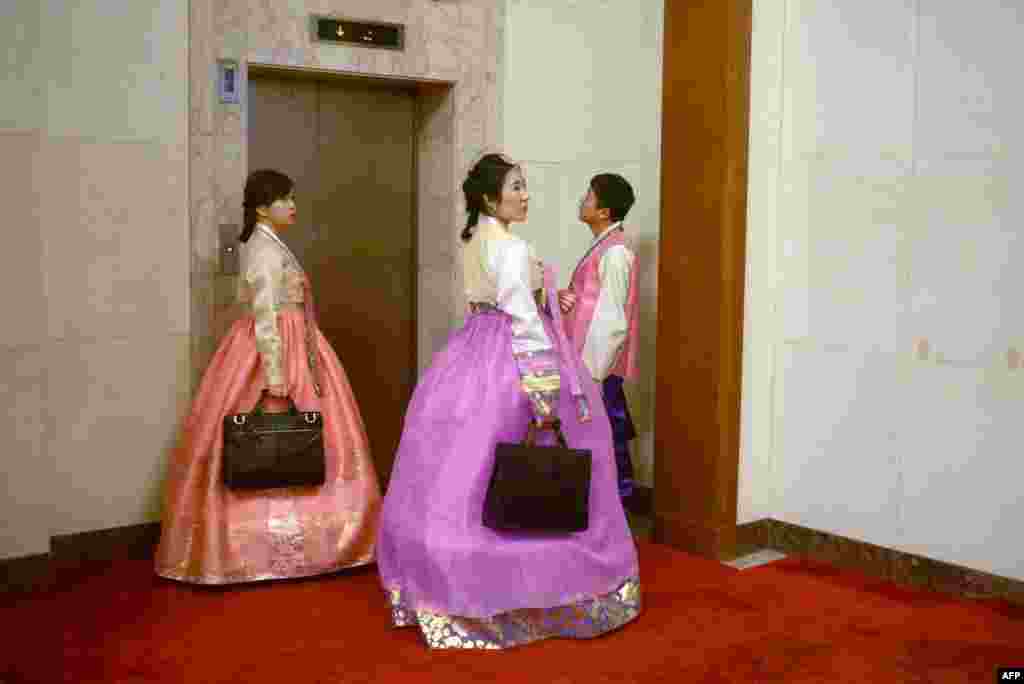 National People&#39;s Congress staff dressed as minorities wait for the elevator at the Great Hall of the People during the 3nd plenary session of the National People&#39;s Congress in Beijing.