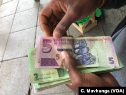 An informal dealer counts bondnotes in Harare, Sept. 9, 2108, which were introduced in 2016 to address cash shortages in vain.