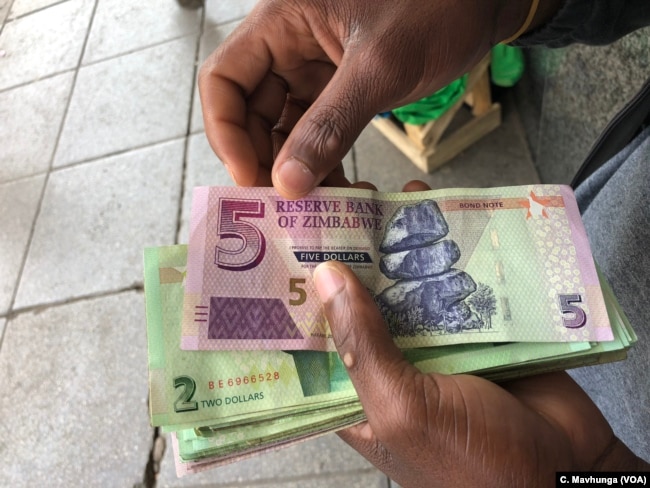 An informal dealer counts bondnotes in Harare, Sept. 9, 2108, which were introduced in 2016 to address cash shortages in vain.