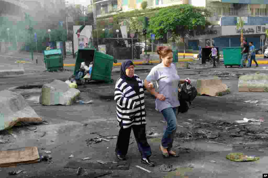 Women walk through a road block of burning garbage containers laid by Sunni protesters angry at the killing of Brig. Gen. Wissam al-Hassan in Beirut, Lebanon, October 20, 2012. 