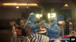 Zdravstveni radnici pomažu paicjentima sa Covidom u poljskoj bolnici u New Delhiju u Indiji, 30. april 2021.
