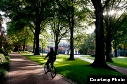 A student rides a bicycle across campus at Elon University in Elon, North Carolina.