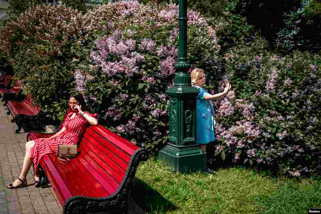 Women enjoy a warm, sunny day in a Moscow park on the first day following Russia&#39;s cancellation of some anti-coronavirus measures.