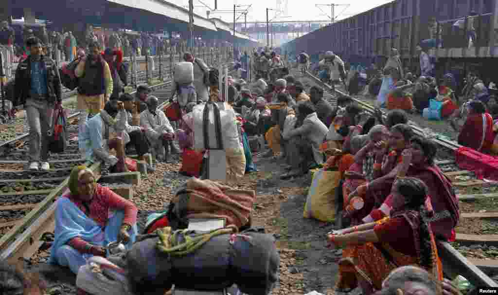 Hindu pilgrims sit on railways tracks as they wait to board their trains at an overcrowded railway station in the northern Indian city of Allahabad Feb. 11, 2013.