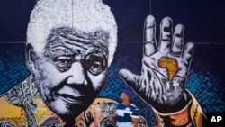 South African artist John Adams works on a giant acrylic-on-canvas painting of Nelson Mandela in the driveway of his house, Johannesburg, July 15, 2013.