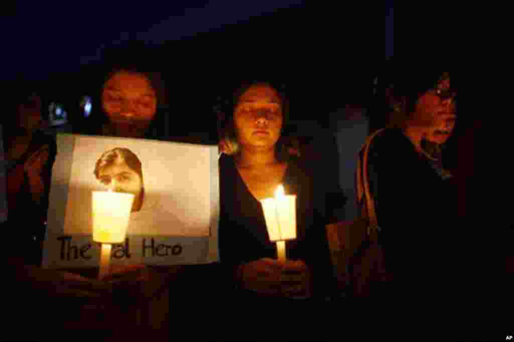 Nepalese students take part in a candlelight vigil to express their support for Malala Yousafzai, depicted in photograph at left, in Katmandu, Nepal, October 15, 2012.