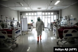 Seorang tenaga medis memeriksa pasien-pasien COVID-19 di unit perawatan intensif (ICU) di sebuah rumah sakit di Bogor, Jawa Barat di tengah lonjakan tingkat infeksi, 18 Juni 2021. (Foto: Aditya Aji/AFP)