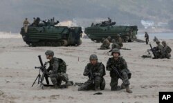 South Korean Marines and U.S. Marines from 3rd Marine Expeditionary Force based Okinawa, Japan, take positions near Amphibious Assault Vehicle (AAV) during the U.S.-South Korea joint military exercises called Ssangyong 2013.