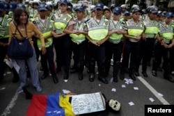 An opposition supporter wearing a costume lies in front of riot police during a rally' in Caracas, Venezuela, Jan. 23, 2017. The sign reads "Venezuelans starve. There is no food or medicine."